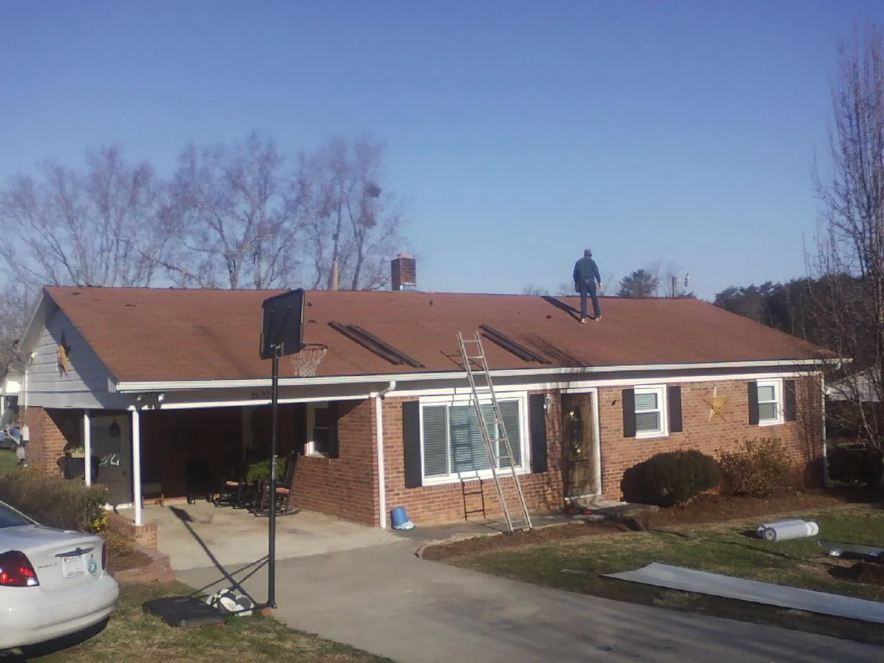 Roofer stripping a shingle roof on a brick ranch before metal panels in South Windham
