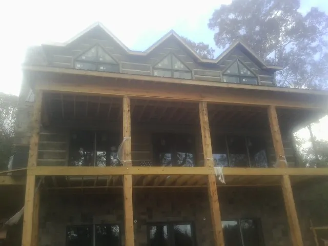 Dormers and porch framing on a large log home under construction — Roof Coating work by our crew in South Windham