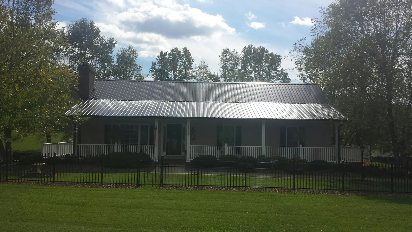 Gray metal roof on a brick ranch with a full width front porch — Gutter Guard Installation work by our crew in South Windham