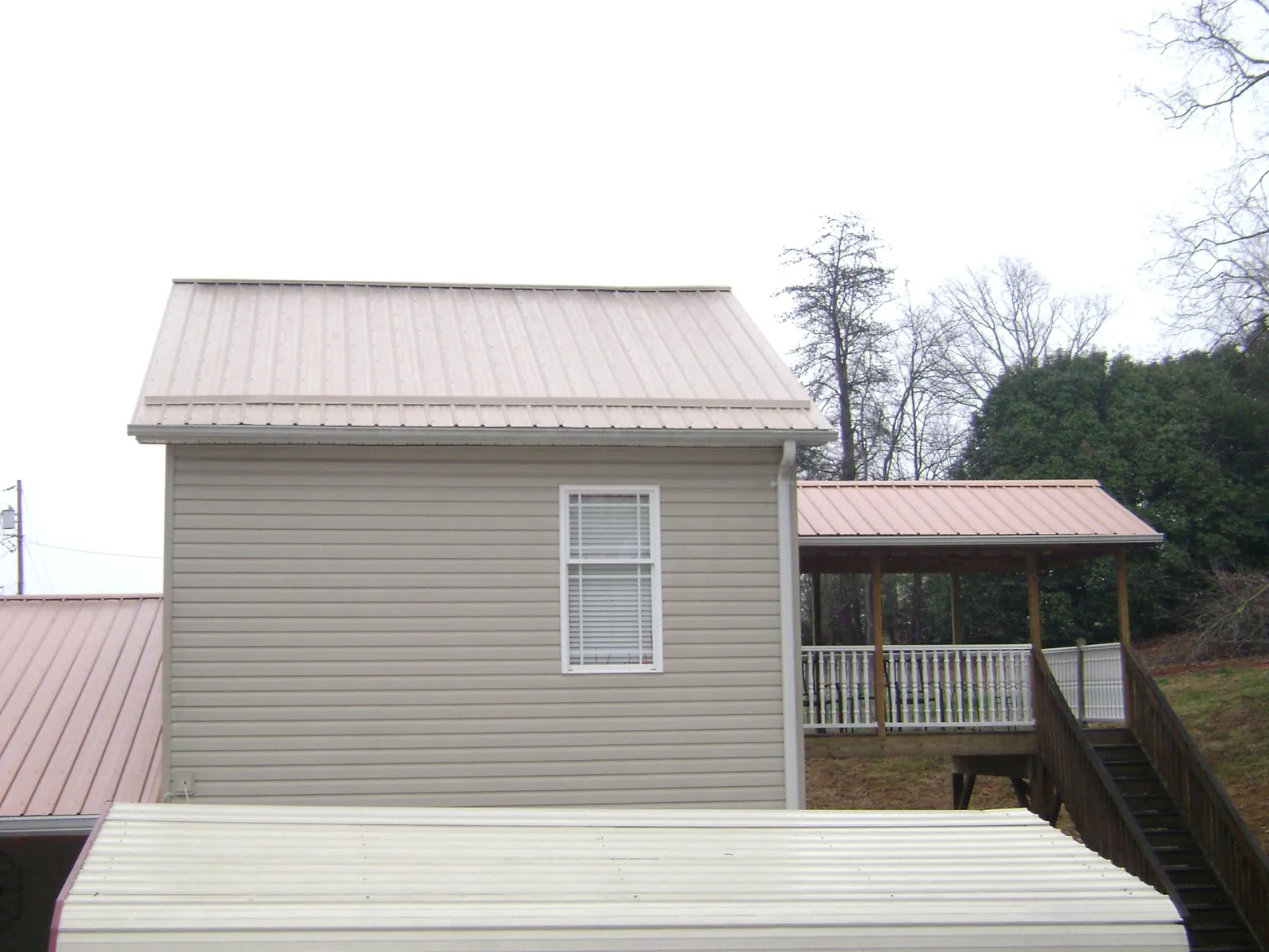 Tan metal roofs on a two story addition and attached porch, from a Roof Replacement job in South Windham
