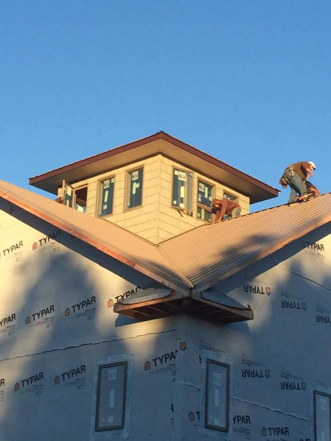 Roofers working around a rooftop cupola on a new metal roof at sunset — Roof Waterproofing in South Windham by Roofing Brothers